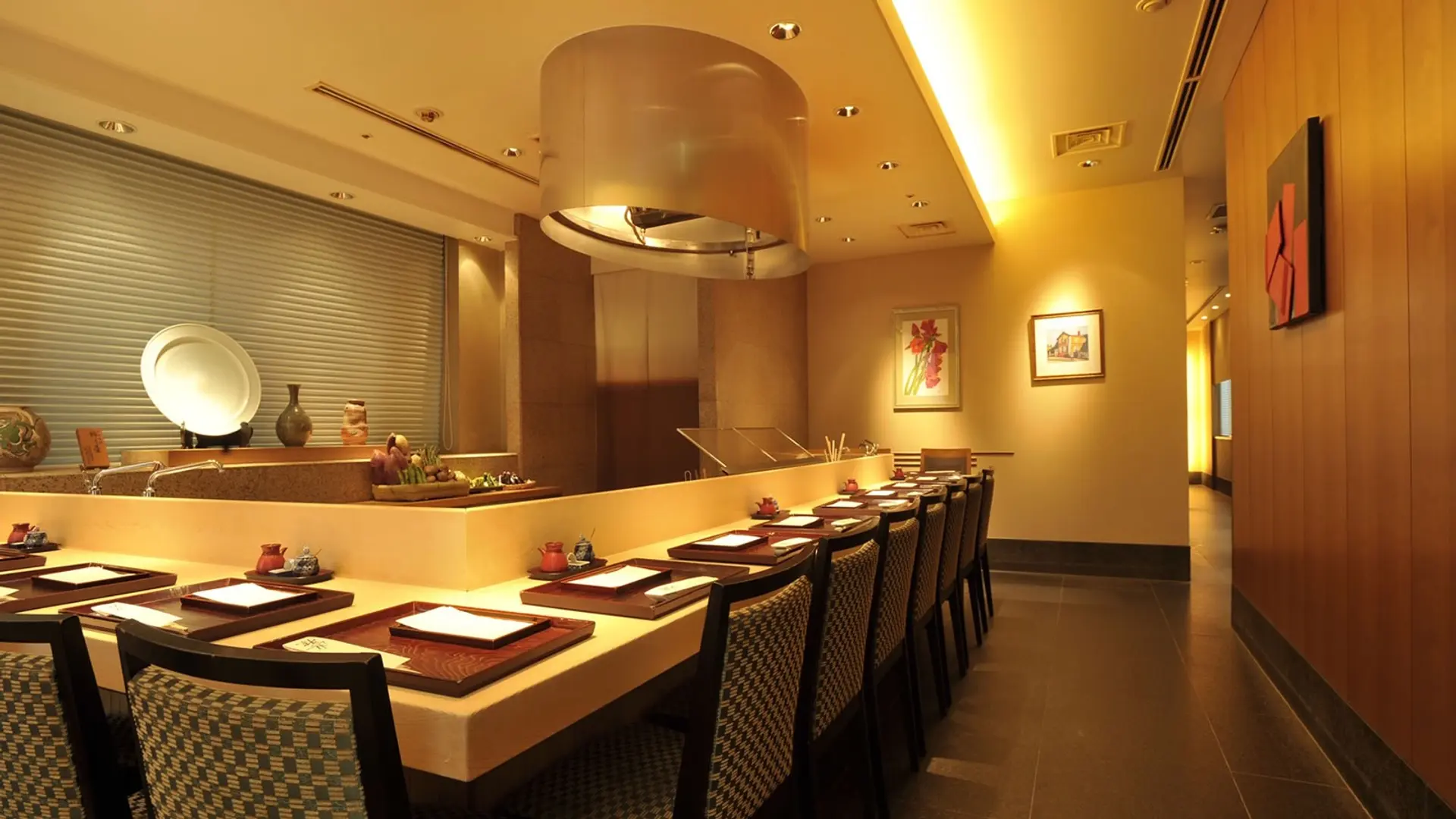 Dining area with patterned chairs, dark floor, yellow walls and roof at Kondo resturant in Tokyo.