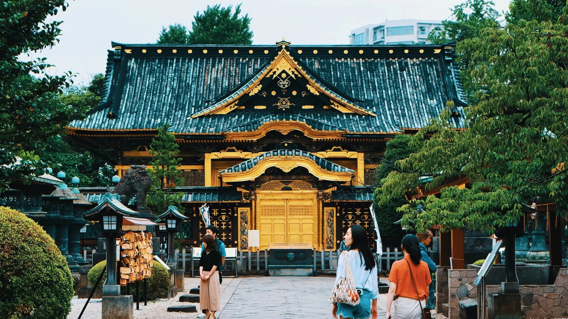 Black and gold yellow coloured temple with trees surrounding, the Toshugu Jinja Shrine at Ueno Park.