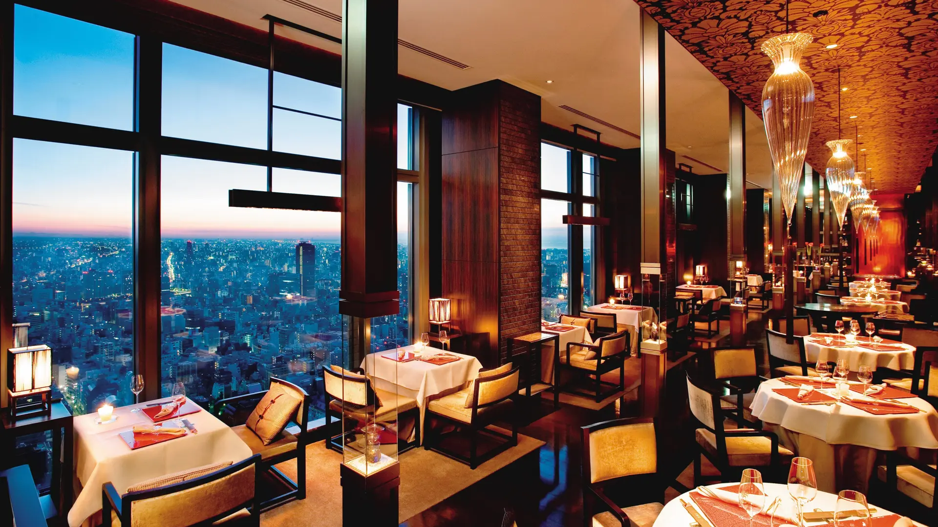 Dining area with glass view to Tokyoi, white dining tables and a red tender lighting at Mandarin Oriental, Tokyo.