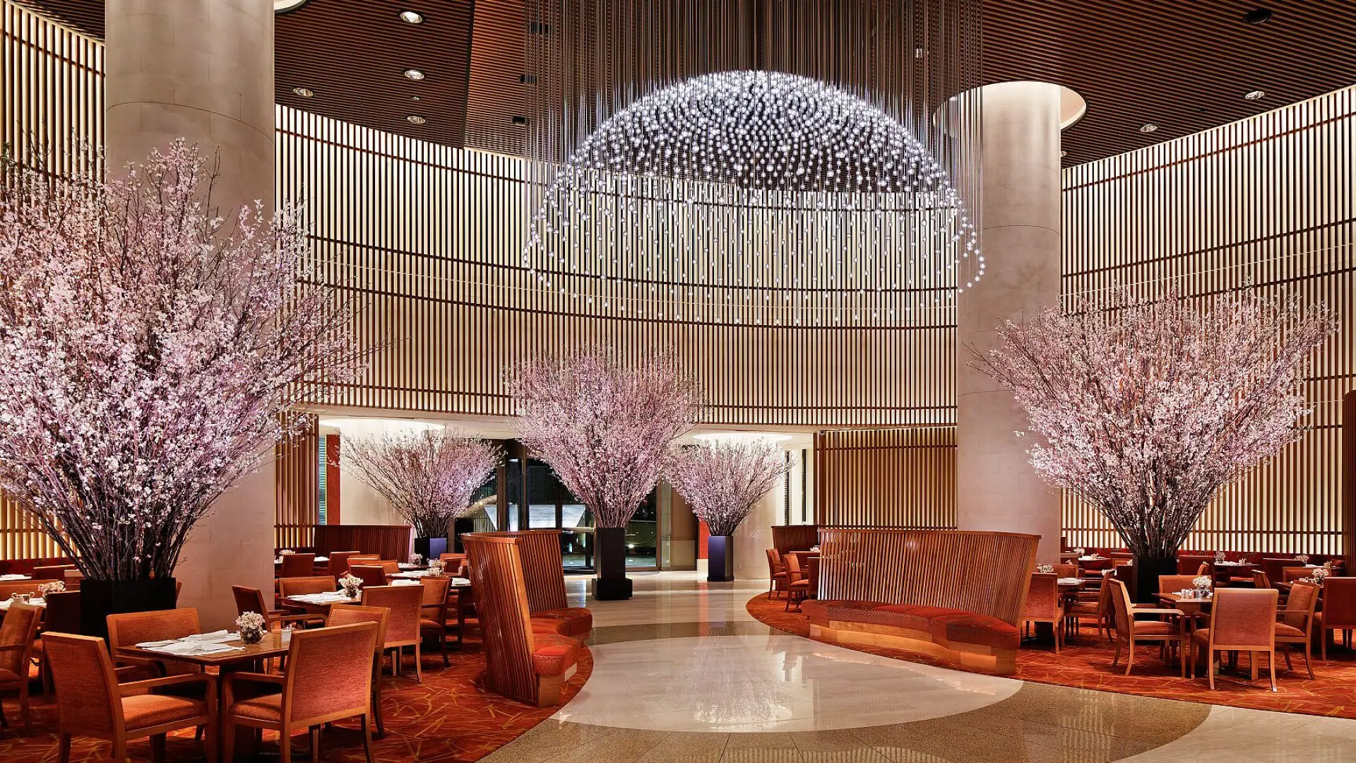 Lounge area at the Peninsuala with japaneese pink trees, red design seating area and marble floors.