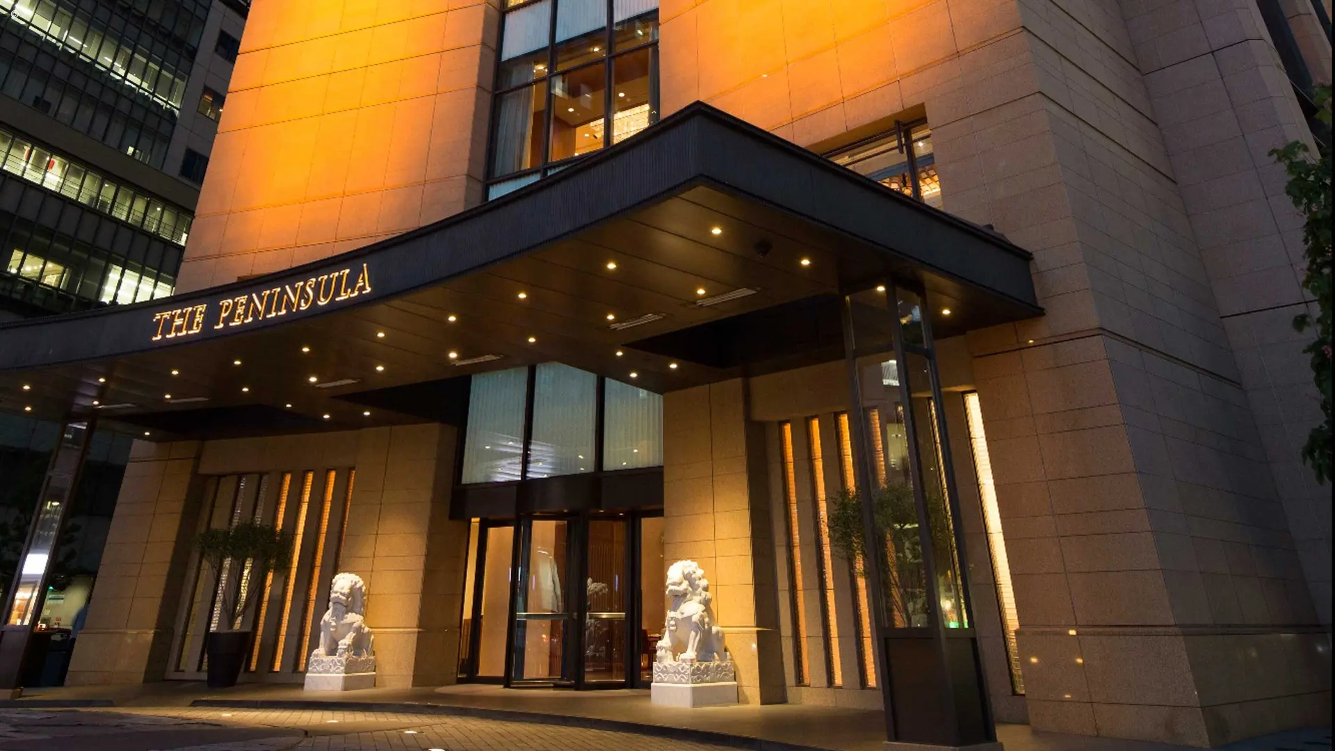 Outside view of the Peninsuala, Tokyo with two lion statues in entrance and modern outside decor.