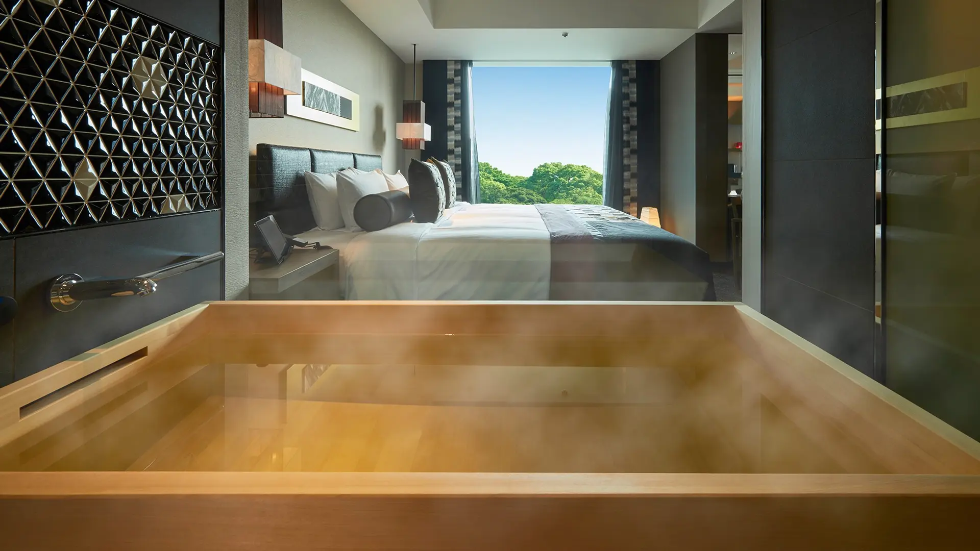 Modern tree looking bathtub with kingsize bed and view to trees in nTokyo at New Otani, Tokyo.