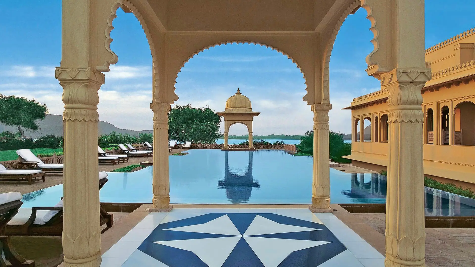 Large swimming pool, sunbeds and view to a large landscape of nature and ocean at Oberoi Marrakesh