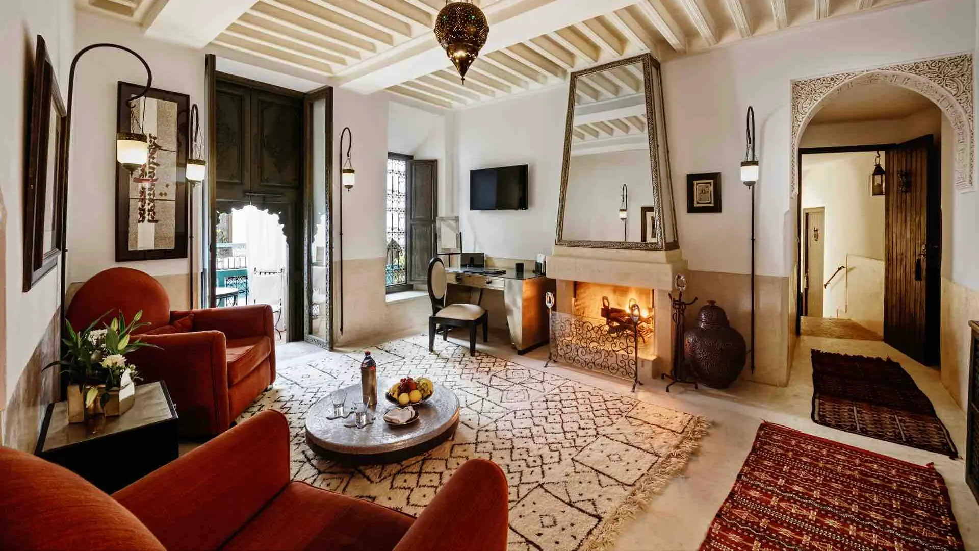 Room with red seats and a fireplace at Riad Farnatchi