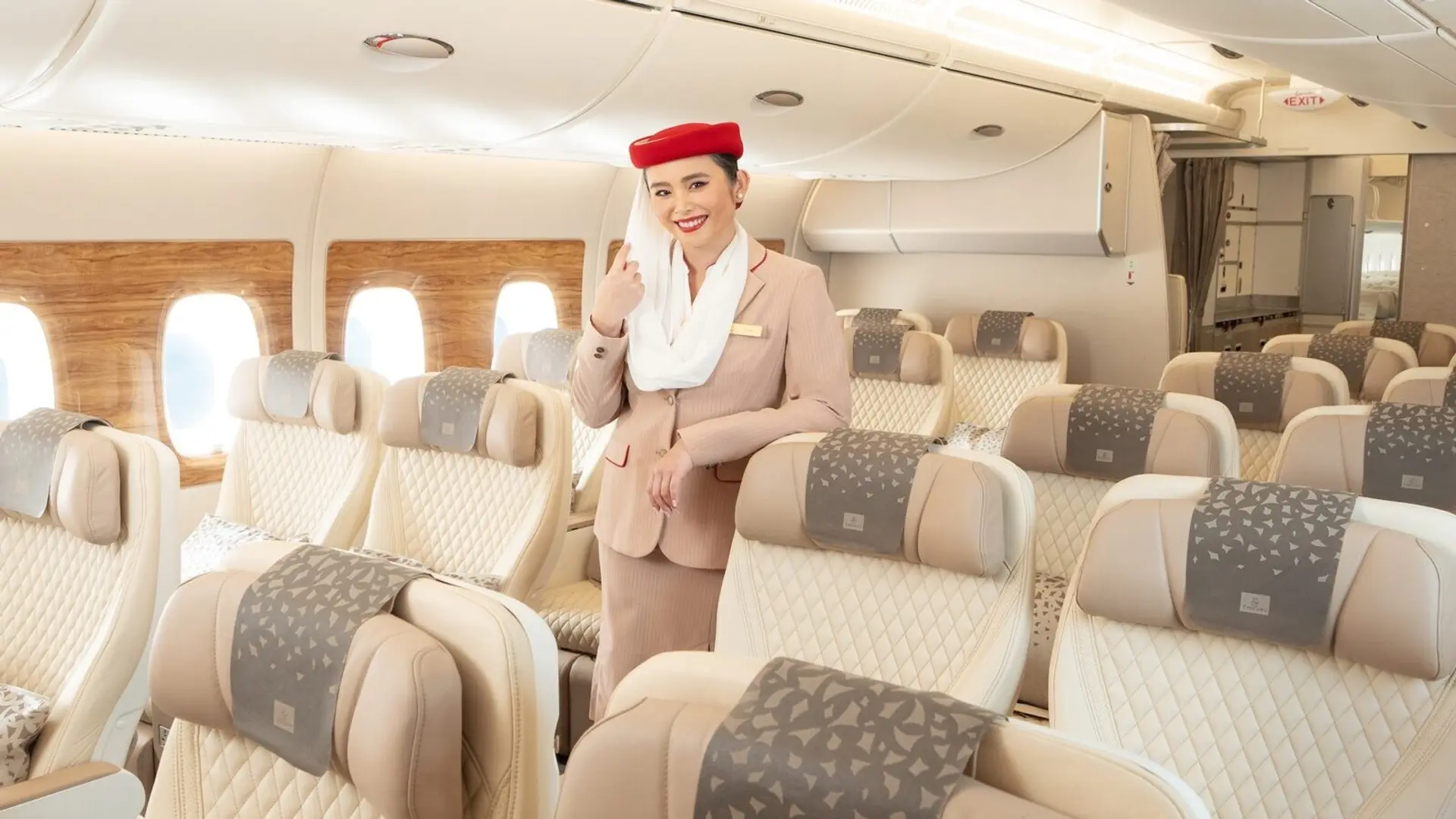 an airhostess standing in the emirates premium economy cabin